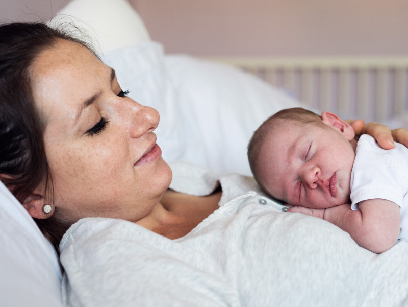 0926riskmom_sc-1 Mother in bed holding newborn baby. (halfpoint/envato elements)