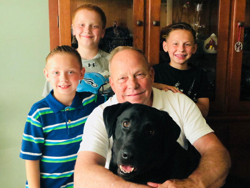 Heart disease survivor Gary Saunders in a 2018 photo with his grandsons (from left: Jaxon, Austin and Jaden Banks) and black lab Hunter. (Photo courtesy of Gary Saunders)