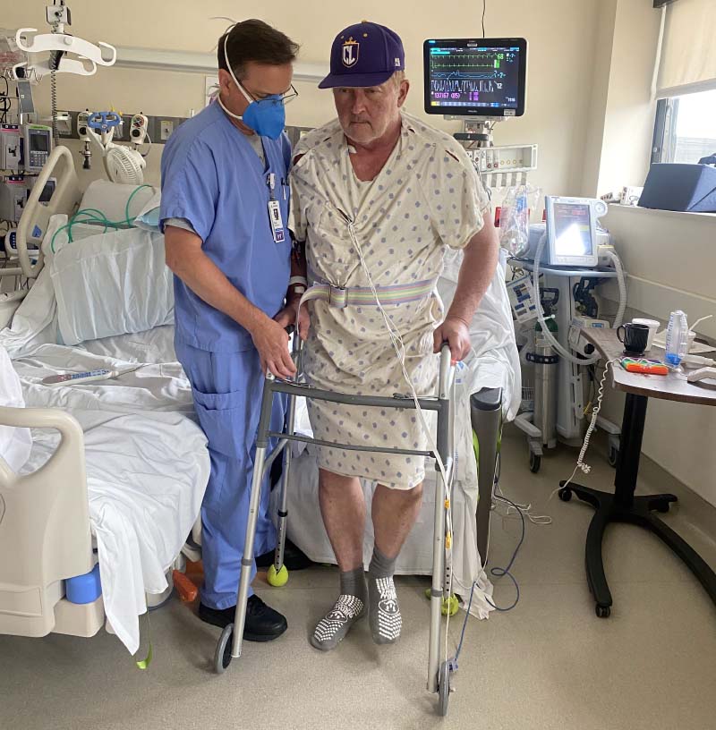TA physical therapist helps Mark Wangrin (right) use a walker in his hospital room. (Photo courtesy of Mark Wangrin)