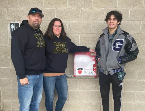 From left: Dylan's parents, Gus and Lisa Dorrell, and brother, Jake Dorrell, with the AED that was placed in the park where Dylan collapsed.  (Photo courtesy of the Dorrell family)